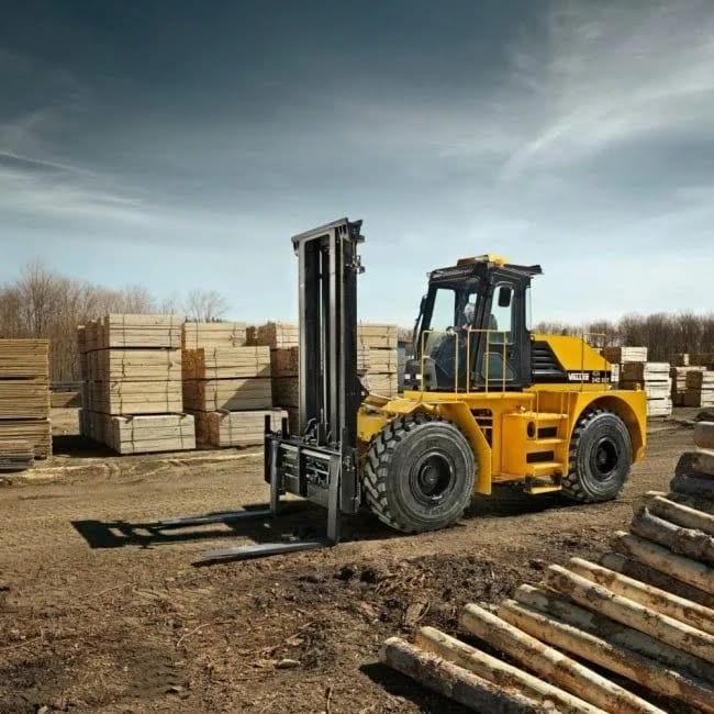 Yellow forklift in a lumber yard with stacks of wooden beams in the background, ready to move heavy timber.